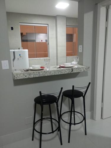 a kitchen with two black stools at a counter at Conforto setor Oeste garagem 505 in Goiânia