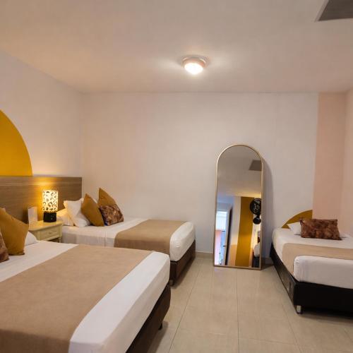 a hotel room with two beds and a mirror at Casa de Pinos Hotel Boutique in Bucaramanga