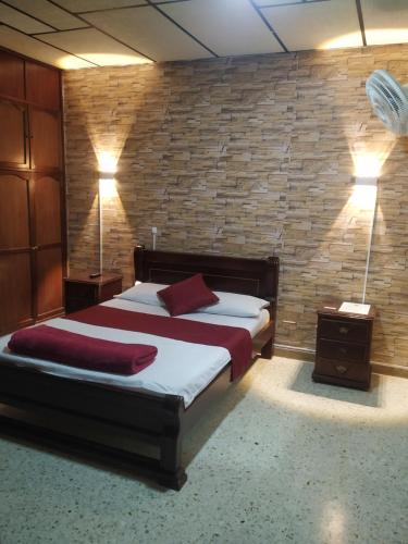 ein Schlafzimmer mit einem Bett mit zwei Lampen und einer Ziegelwand in der Unterkunft Hotel Ejecutivo in Pereira