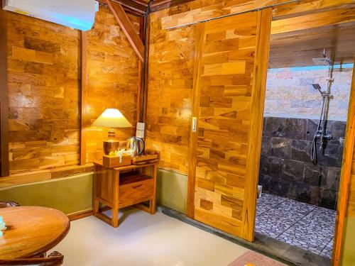 a bathroom with a shower with a wooden wall at Wimala Farm House in Munduk