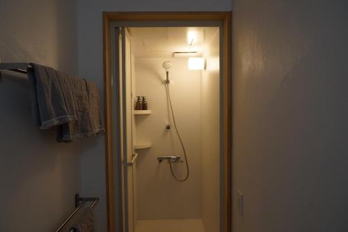 a bathroom with a shower with a light on the wall at ゲストハウス弓と糸 Guesthouse Yumi To Ito 2F in Nagano