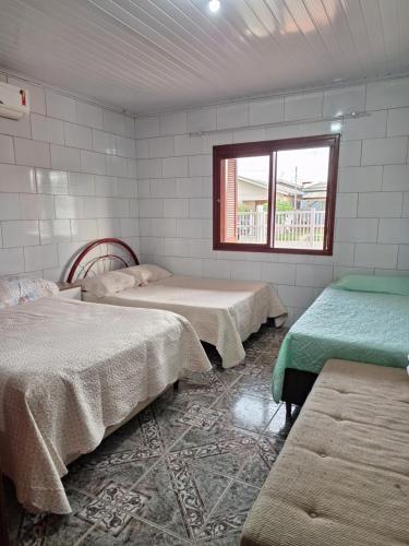 a room with three beds and a window at Habitación Familiar in Pântano Grande