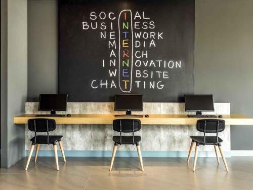 a desk with three computers on top of it at ibis Bangkok IMPACT in Nonthaburi