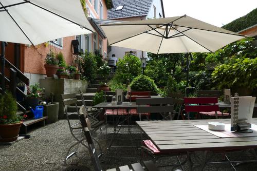 eine Außenterrasse mit Tischen und Stühlen und einem Sonnenschirm in der Unterkunft Hasi's Hotel in Grafing