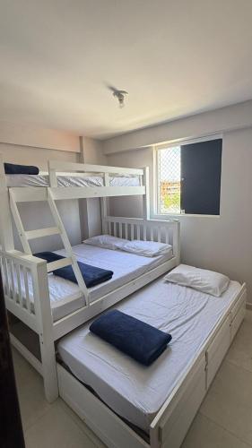 due letti a castello bianchi in una stanza con televisione di Apartamento Fest Verão a Cabedelo