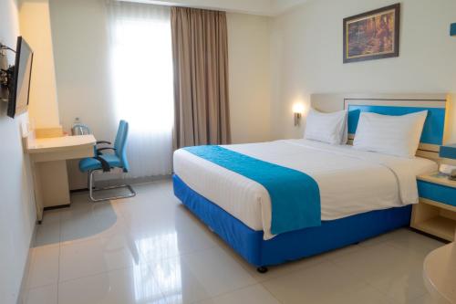 een slaapkamer met een blauw en wit bed en een bureau bij Hotel Brothers Solo in Solo