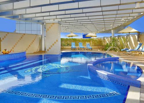 a large swimming pool with chairs and umbrellas at DoubleTree by Hilton Dubai Port Saeed in Dubai