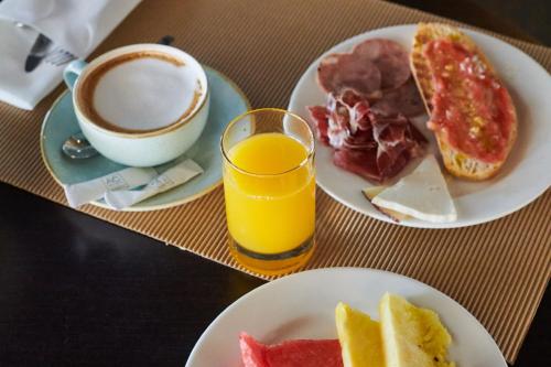 a table with two plates of breakfast food and a cup of coffee at Sabàtic Gavà Mar, Barcelona, a Tribute Portfolio Hotel in Gavà