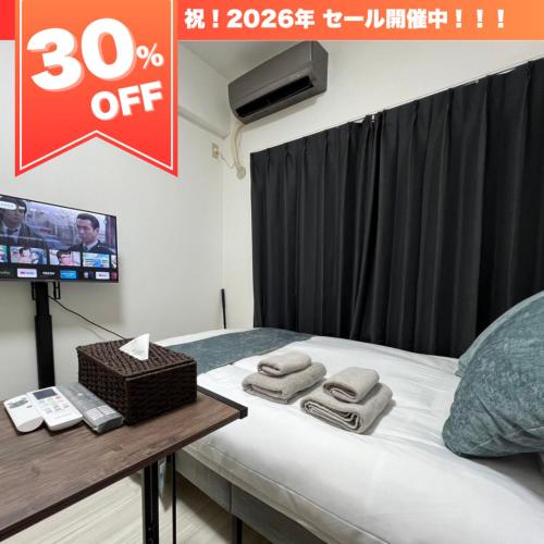 a room with a bed with a tv and towels at ラレジダンスドパンテール in Fukuoka