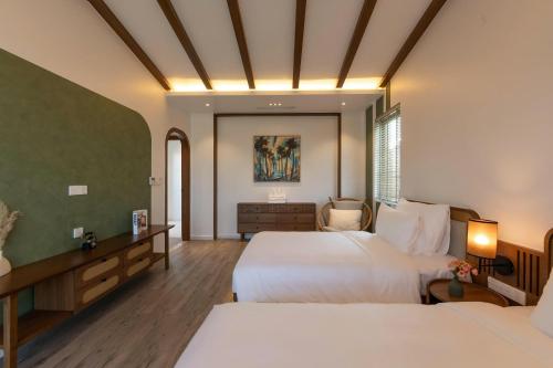 une chambre d'hôtel avec deux lits et un bureau dans l'établissement Green Villas Tropical Phú Quốc, à Duong Dong