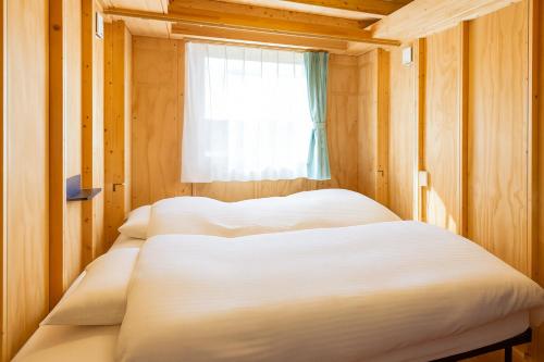 two beds in a small room with a window at MOBILITA COURT IWATE in Hachimantai