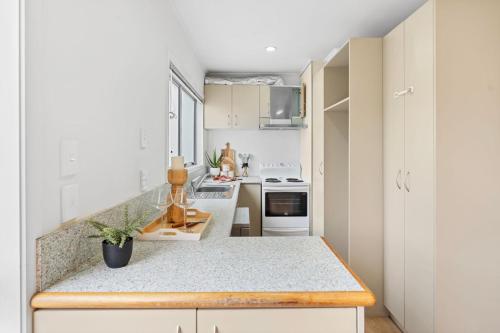 a kitchen with white cabinets and a counter top at Holiday House in Central North Shore Auckland in Auckland