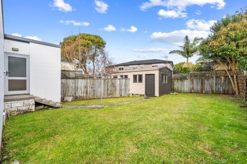 a backyard with a fence and a house at Holiday House in Central North Shore Auckland in Auckland
