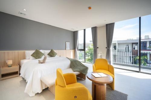 a bedroom with a white bed and two yellow chairs at TS Villa in Danang