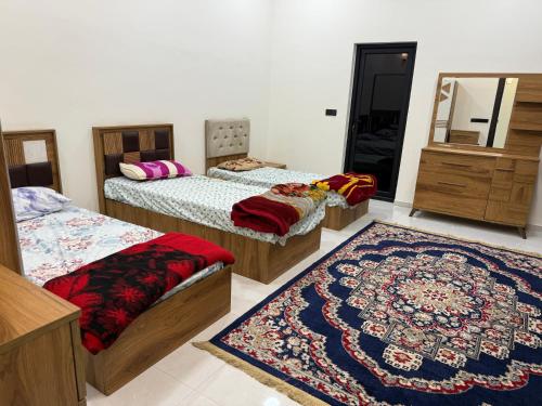 a room with four beds and a mirror and a rug at مزرعة منتجع الامراء in Baghdād