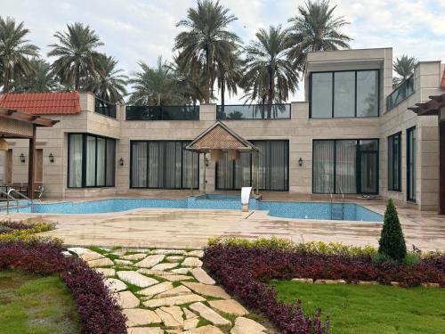 a house with a swimming pool and palm trees at مزرعة منتجع الامراء in Baghdād