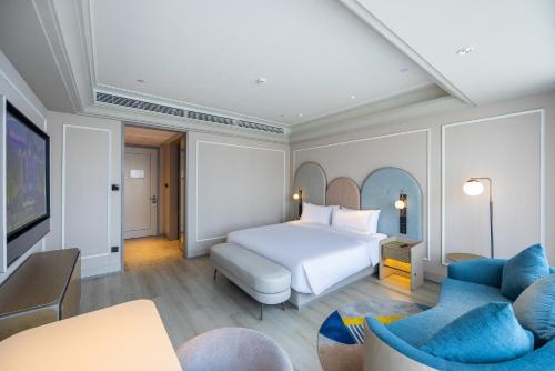 a hotel room with a bed and two chairs at Mercure Tianshui Downtown in Tianshui