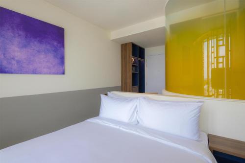een slaapkamer met een wit bed met een schilderij aan de muur bij Wink Danang Riverside, Unscripted by Hyatt in Da Nang