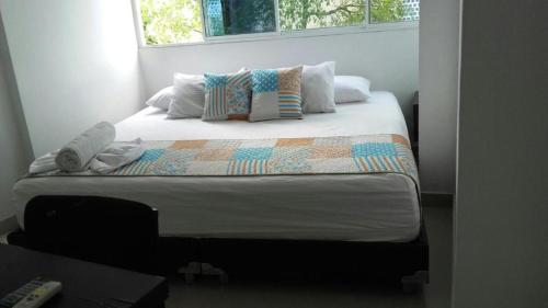 een slaapkamer met een bed met kussens en een raam bij Hotel Plazuela Real in Barrancabermeja