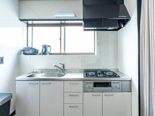 a kitchen with white cabinets and a sink and a window at ぷふか映月東向島 Pufuka Eigetsu Higashi Mukoujim in Tokyo