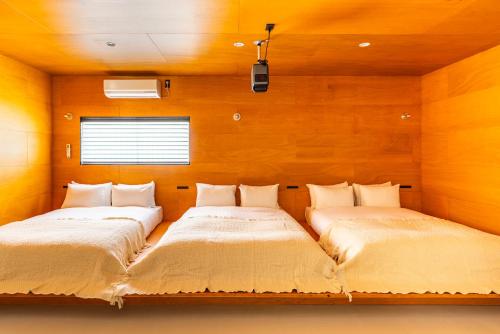 two beds in a room with wooden walls at ぷふか映月東向島 Pufuka Eigetsu Higashi Mukoujim in Tokyo