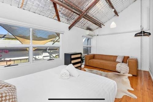 a white bedroom with two beds and a couch at 5 North Freo 2BR Supercool Pad & Parking in North Fremantle