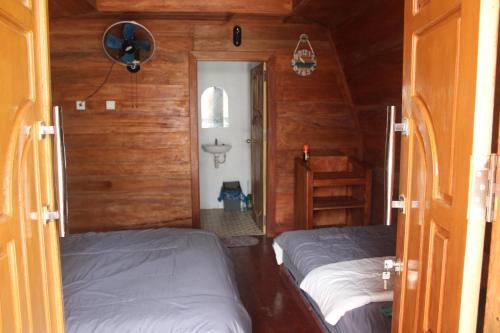 two beds in a room with wooden walls at North Pagai Bungalows in Pulau Silabusabeu