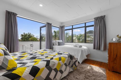 a bedroom with two beds and a large window at Beach Haven - Papamoa Beach Escape in Papamoa