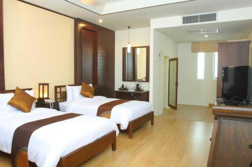 a hotel room with two beds and a flat screen tv at Palette Bangkok Natural Resort and Spa in Bangkok