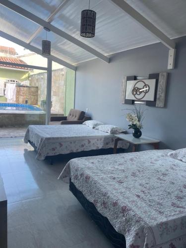 a bedroom with two beds and a chair in it at Bela casa com piscina in Mongaguá