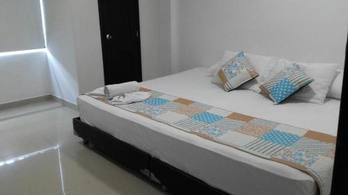 een bed met kussens en een dekbed erop bij Boutique Real PRB in Barrancabermeja