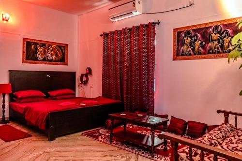 een slaapkamer met een rood bed en een bank bij Fire Room Elements by Hexa stays in Trivandrum