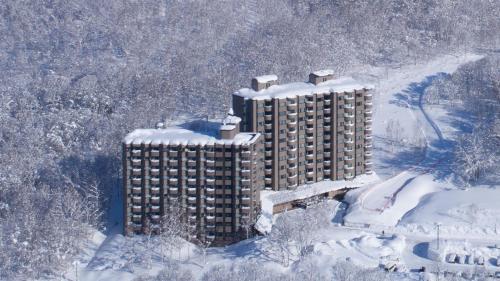 a tall building covered in snow in the snow at One Niseko Resort Towers in Niseko