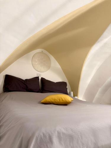 a bedroom with a bed with a yellow pillow at Casa iuserì in Cisternino
