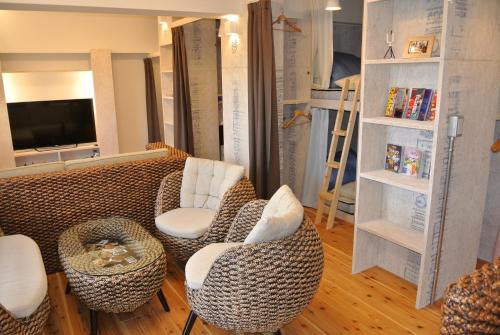 a living room with a couch and chairs and a tv at Backpackers Hotel NOOSA JAPAN in Takatsuki Tonda in Takatsuki
