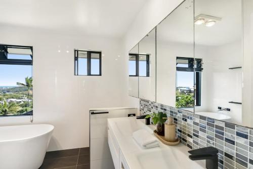 a bathroom with a white tub and a sink and a mirror at The Break in Lennox Head