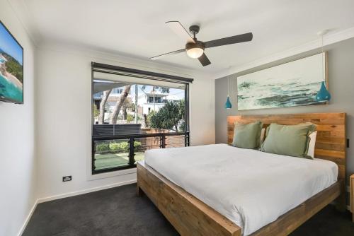 a bedroom with a bed with a ceiling fan and a window at The Break in Lennox Head