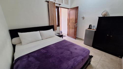 a bedroom with a bed with a purple blanket at Jepun Bali Homestay Sanur in Sanur