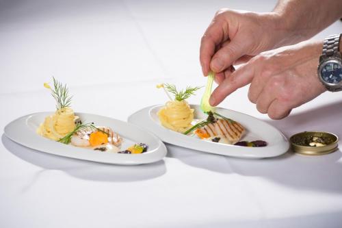 a person eating two plates of food on a table at Gourmet Hotel Zur Post in Saint-Vith