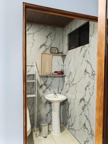 a bathroom with a white sink and a marble wall at Yamis home in General Viejo
