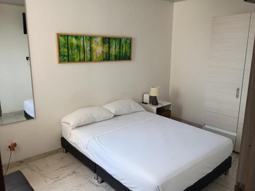 een slaapkamer met een wit bed en een schilderij aan de muur bij Apartamento en Ibagué Campestre in Ibagué