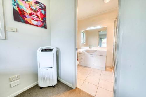 een witte koelkast in een badkamer met een spiegel bij Relaxing 3BR Home by Wattle Downs Reserve in Auckland