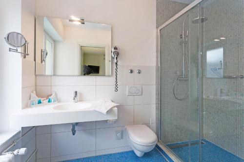 a bathroom with a shower and a sink and a toilet at Hotel City Inn Basel in Basel