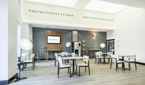 a dining room with tables and chairs and a tv at Ilunion Valencia 3 in Valencia