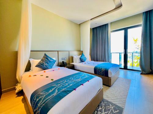 a hotel room with two beds and a large window at Matemwe Sands Hotel in Mkuyuni Pwani