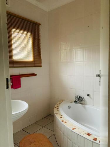 a white bathroom with a tub and a sink at Ezendalo Guest House in Pinetown