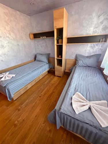 two beds in a room with wooden floors at Chepelare Holiday Guest House in Chepelare