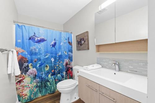 een badkamer met een aquariumdouchegordijn en een toilet bij 1st Ashore-Beachfront-Pet Friendly in St. George Island