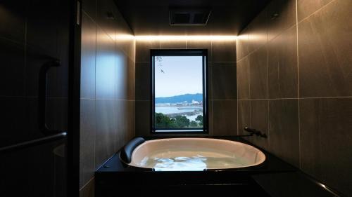 een badkuip in een badkamer met een raam bij THE BLESS Awaji in Sumoto