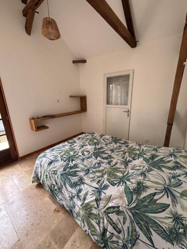 a bedroom with a bed with a leafy bedspread at Location l'îlot tropical in Le Bois de Nèfles